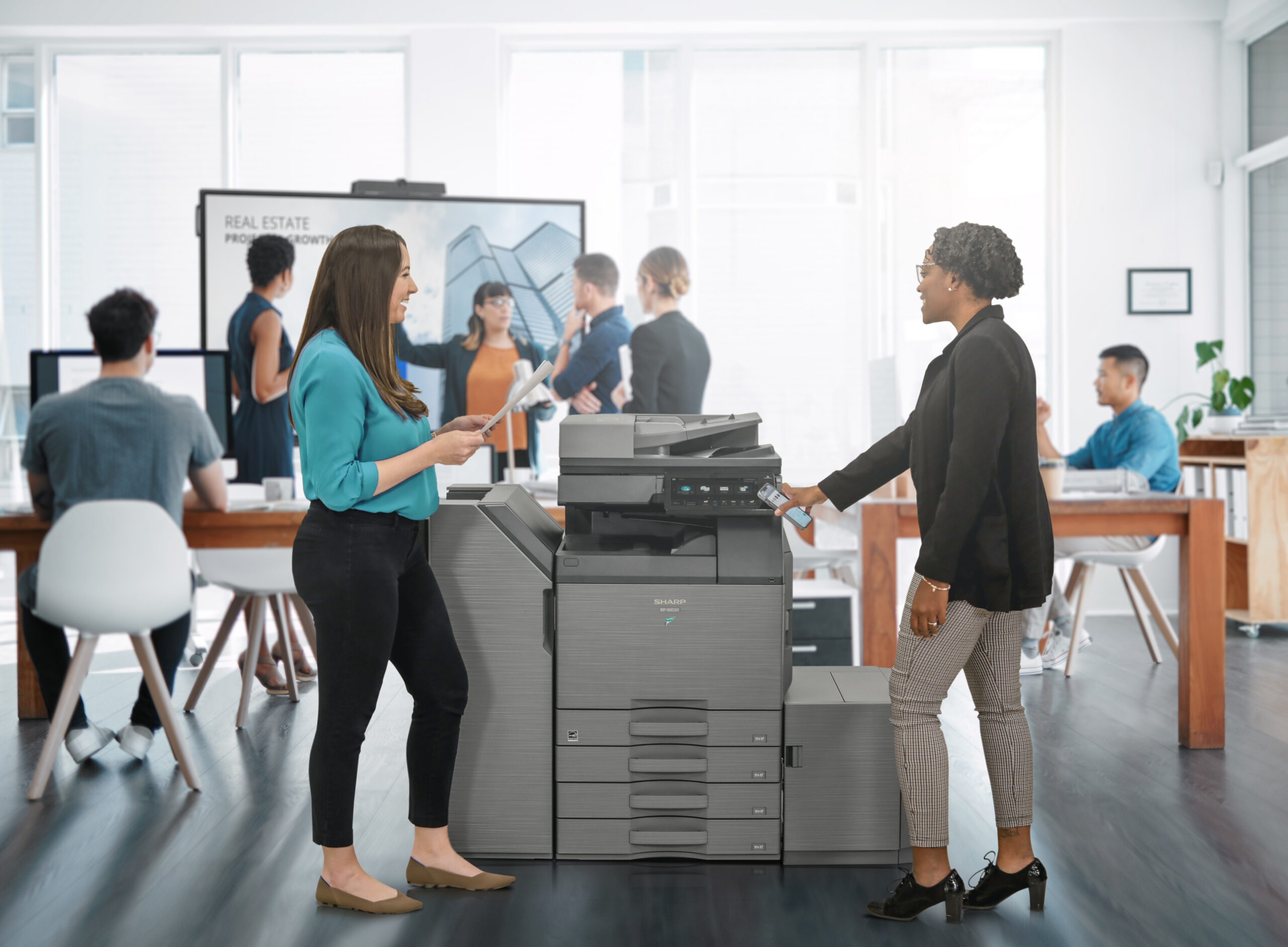 Business professionals using a Sharp multifunction printer in an office